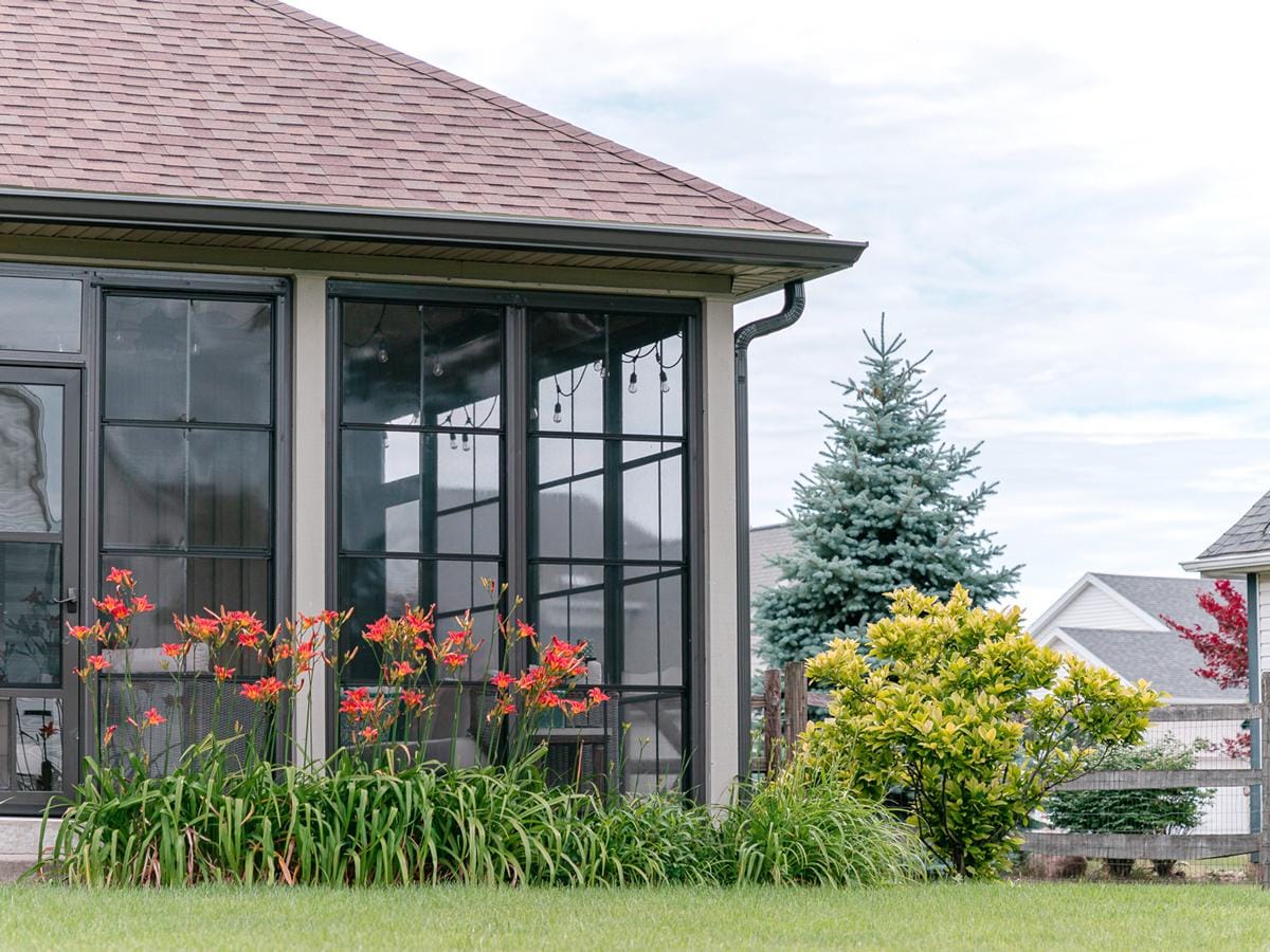 Enclosed porch with dark-framed glass and vinyl wall panels on a South Jersey home, viewed from the garden